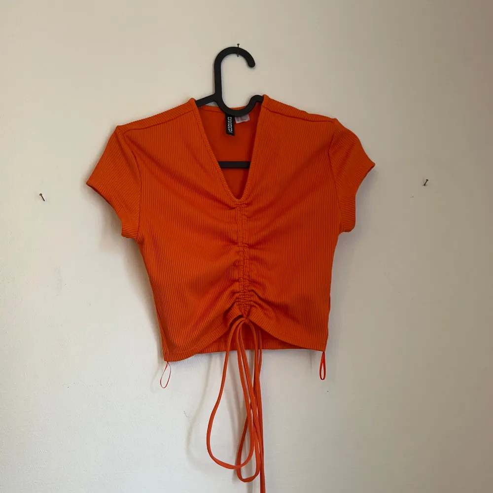 Orange scrunch tie top with a cropped fit . Blusar.
