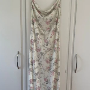Blommig långklänning  - Blommig långklänning ifrån NA-KD i storlek M . Klänningen är helt oanvänd och har prislappen kvar. Klänningens material är jättemjukt och tyget är väldig fint . Fin detalj över bysten. Klänningens ordinarie pris är 699 men säljs för 400+frakt. 