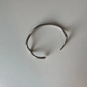 Ormarmband  - Gjord i stål och har inga skador. Det är en mindre storlek men man kan töja in och ut på armbandet. 