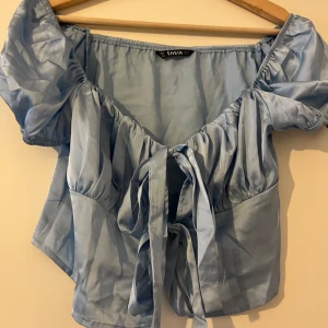 Knyttopp i satin - Ljusblå knyttop i satin. Storlek M. Aldrig använd.