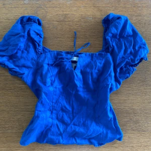 Blå linnetopp - En blå linnetopp från H&M med korta puffärmar och knytning framtill. Toppen har en smockad rygg för en bekväm passform.🙌🌟