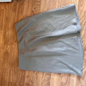 Satin kjol - Säljer denna kjol, aldrig använd. Tror att den är från Kappahl eller likande. Den är blå/grå/ grön