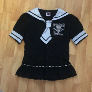 Blus, K.Star - En svart sailor-blus med svarta spetsdetaljer och avtagbar slips. Den är vintage och i använt skick, finns nopprar, några missfärgningar ( bild 3, finns lite på ärmarna också). Trådarna på knapparna är lösa. En rosett föll av så har lagat, andra är lös.