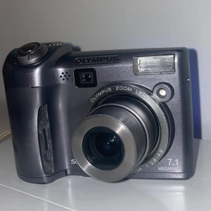 Digitalkamera  - Olympus digitalkamera som går på 2 AA batterier! Söt och lagom stor. Ett XD minneskort medföljer! Allt funkar, man kan både fota och filma med den! 