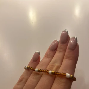 Armband  - Armband av pärlor i brun, guld och vitt.
