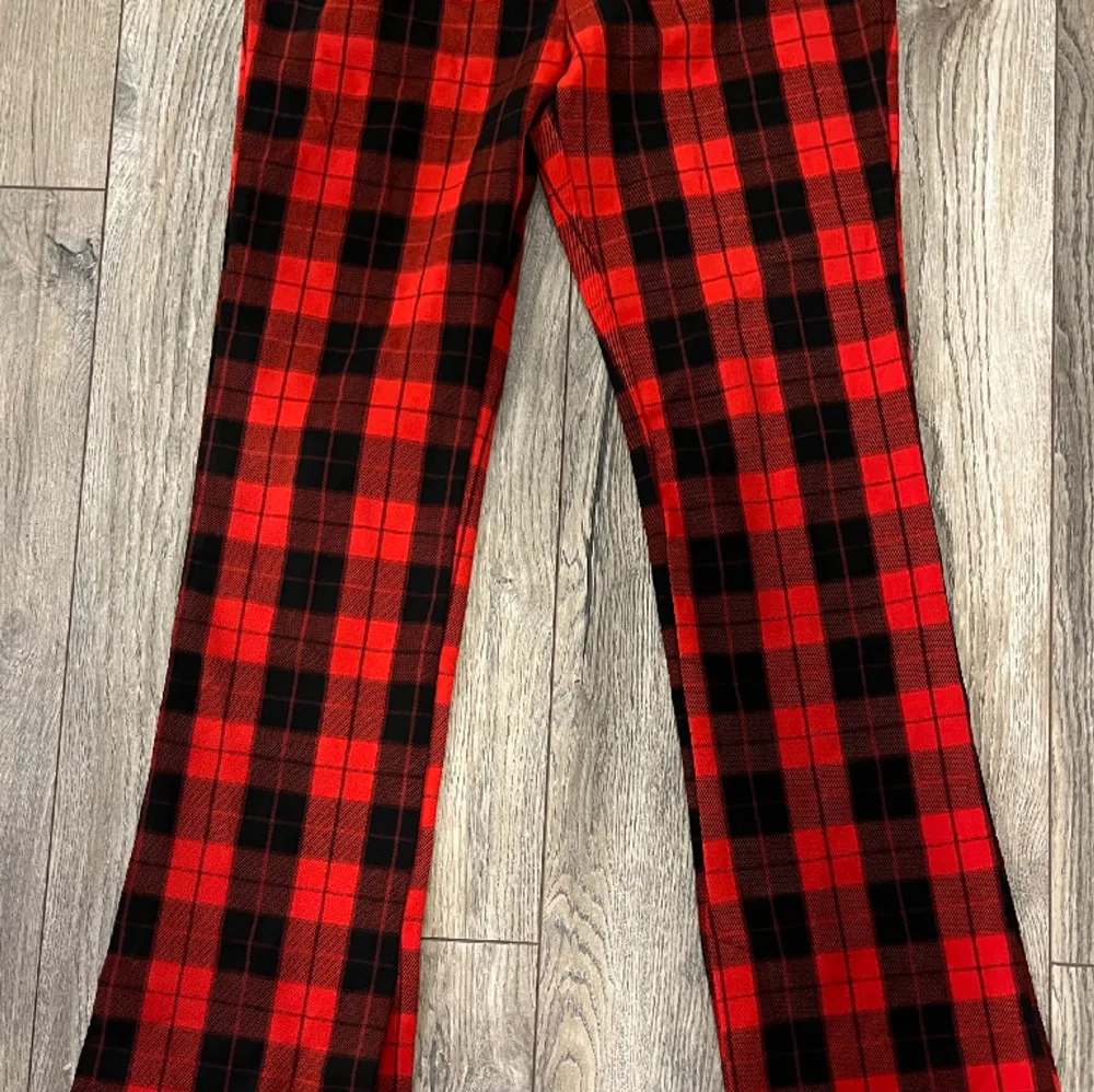 svart och röd rutiga utsvängda byxor med dragkedja i storlek 38. Aldrig använda och i perfekt skick. Jeans & Byxor.