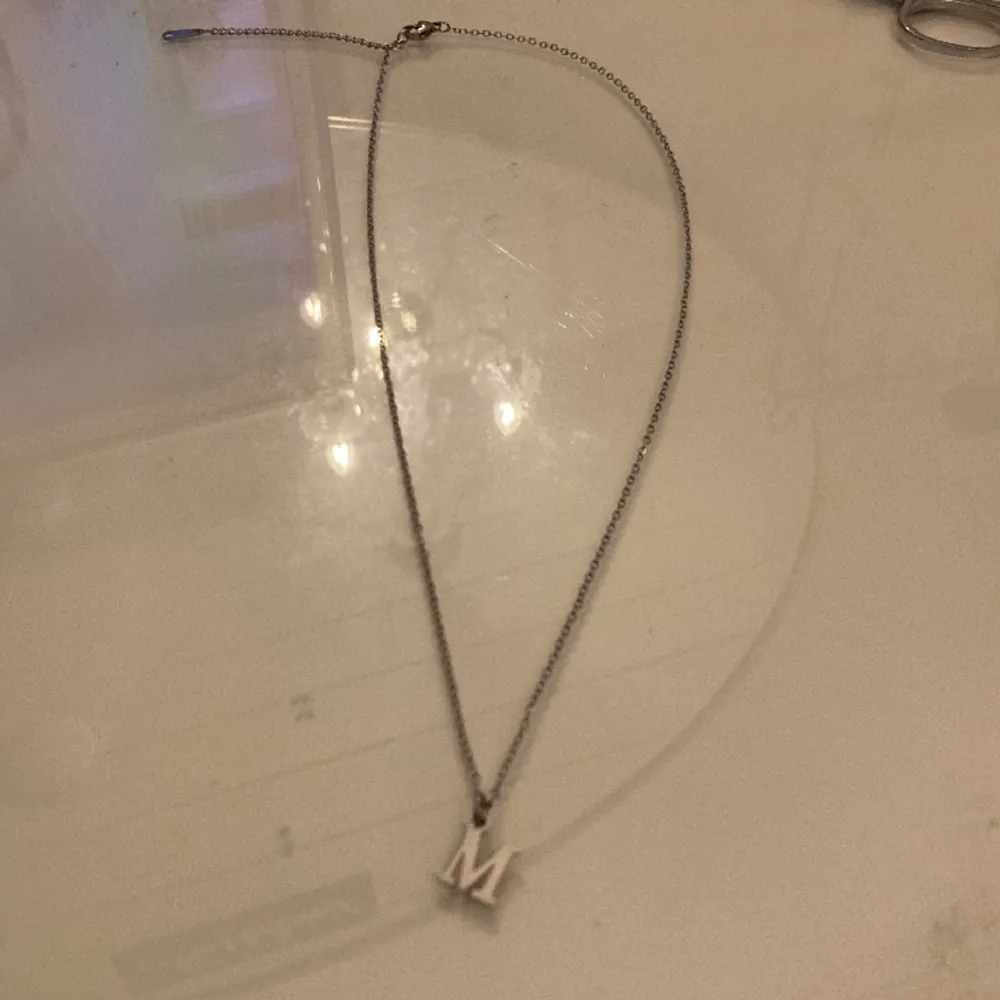 Det här är ett halsband med ett M på och halsbandet är använd ca 2 gånger tror jag. Accessoarer.
