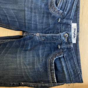 Supersnygga Bootcut lågmidjade jeans. Fina stenar på fickorna. Lite slitna (ses på bild) Har sytt ut längst ner. Hör av er för fler bilder eller info❤️