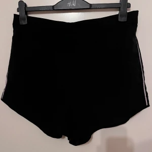 Shorts  - För att a bilden är framsidan, andra bilden baksidan. Shortsen är svarta och har vita ränder på sidorna. Shortsen har även fickor på sidan. Super bra skick då de är anvönda väldigt få gånger! 