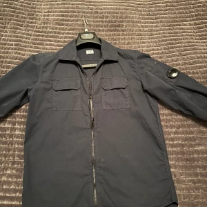 cp company overshirt  - Tjena, säljer nu min overshirt i marin blå från cp company och är i mycket bra skick den är i size 14Y men passar dig som är ca 170-177cm, hör av dig vid frågor och liknande ( köptes på deras egna hemsida för ca 2200kr ( självklart äkta) , 🙌🏽🤝🏽