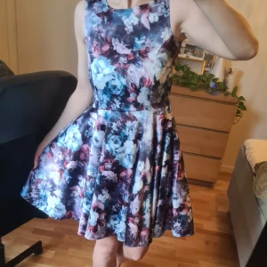 Festklänning/cocktailklänning - Ej använd festklänning/cocktailklänning i glansigt blommigt mönster.