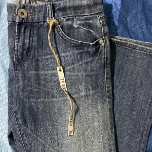 Lågmidjade jens  - Säljer ett par gråa Lågmidjade jeans med  designe på backfickan. Helt nya då de ej till användning. Kan skicka fler bilder ( ej på ) om det önskas 