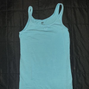 Ljusblå linnetopp från H&M - En enkel och bekväm ljusblå linnetopp från H&M. Toppen har smala axelband och en rund halsringning. stl 146/152