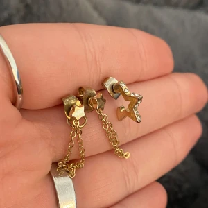 Örhängen  - Örhängen i guld köpta på Åhléns för 120 kr. Örhängen med stjärnan fick man själv så det finns bara ett. Alla 3 för 30 kr, paret för 20 och den ena stjärnan för 15