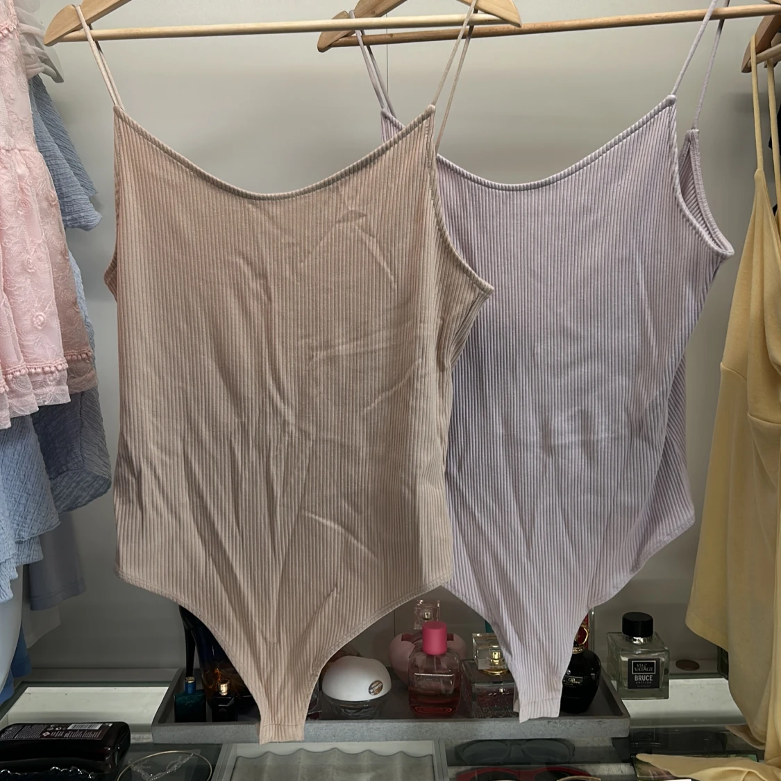 Två bodys med öppen rygg en Beige och en lila.