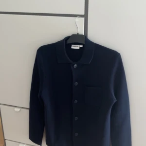 Marinblå cardigan   - Tjena, säljer nu min cardigan/overshirt då den är lite för stor för mig, den är enbart testad och säljer den här för jag glömt lämna tillbaka den till butik, extra knappar samt kvitto finns. Den är perfekt till sommaren och passar till ca 180-185cm 