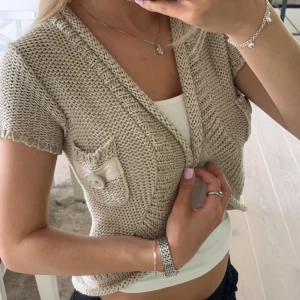 Stickad kofta - Stickad kortärmad kofta. Aldrig använd och köpt på plick.