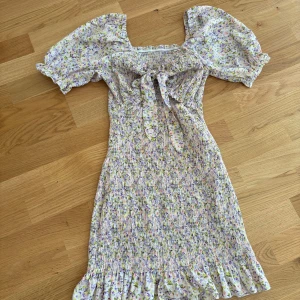 Blommig klänning med öppen yta under bysten - Jättefin blommig sommarklänning med knytning vid bysten samt en öppning mellan byst och mage 🩷  Längden går underförstått till knäna 🌸