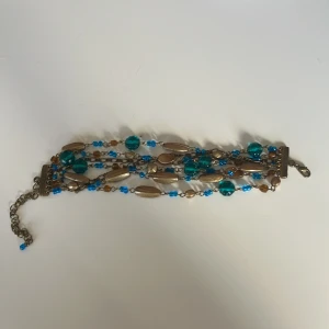 Justerbart armband - Guldarmband med blåa pärlor. Går att justera storlek. 