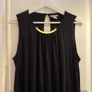 Tunika - Svart tunike led guld-detalj vid halsen. 