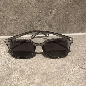 Ett par gråa solglasögon som är riktigt snygga och perfekta till sommaren