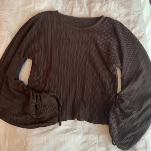 Brun ribbad blus  - Brun ribbad blus från Ginatricot med knytning på ärmarna. Storlek S. Fint skick. 