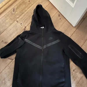Nike tech svart!! - Hej säljer nu denna Nike tech som är svart och den är jätte bra skick! 8/10, rökdfritt och djurfritt hem’ säljer jätte billigt pgr av behöver pengar snabbt. 100% äkta ! Om ni undrar något bara hör av er ! Den är i storlek 158-170 😁