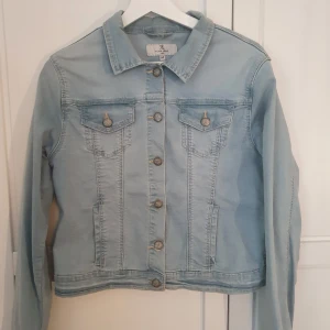 Ljusblå kortare jeansjacka från Flash - Tunnare ljusblå jeansjacka från Flash. Strl M. Kortare modell. Sparsamt använd. Finns ett märke på ena axeln. Se bild 5. Inget som stör helhetsintrycket. Kan ev gå att tvätta bort. Rökkfritt hem med katter. Hämtas i Göteborg eller skickas mot frakt.