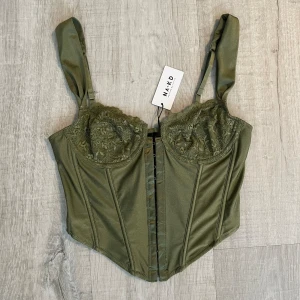 Grön korsett topp  - Grön korsett topp köpt från NAKD. Stl 75A. Justerbara band. Aldrig använd, lapp kvar 