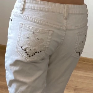 Vita Esprit jeans - Ett par vita jeans med broderade detaljer och nitar på bakfickorna, samt vid framfickorna. Utsvängda längst ner. Lågmidjade.