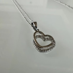 Hjärt halsband  - Låt kärleken leda vägen med detta hjärthalsband i sterlingsilver som kan bäras. Den tidsenliga designen och den upphöjda steninfattningen gör att du kan bära det till i stort sett vad som helst.