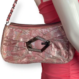 Guess Väska  - I fint skick, några lösa sömmar runt bandet. Skulle säga skicket är 7/10. Höjd 14cm, bredd 27cm & djup 6cm  