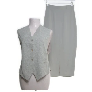 Exklusiv set från Kello - Mycket fint klassikt set för den moderna kvinnan. I en stilren design och i diskret färg av grå/grön i fiskben mönster.  Överdelen är storlek 38 och underdelen stranden 36. Sparsamt andvänd. ACECAT är materialet