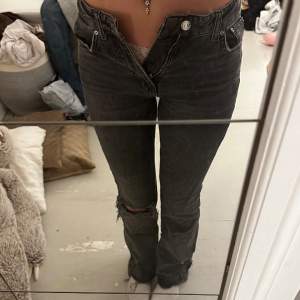 Mörkgråa Midwaist jeans ifrån Gina Tricot med hål i benet och slitningar nere vid fötterna. Säljer då de är för små. 