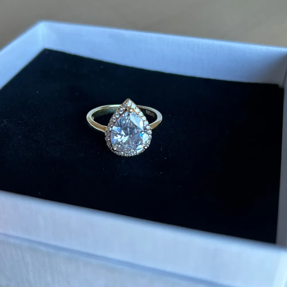 Ring in genuine 925 sterling silver designed with a large teardrop white zirconia. The rail is decorated with white zirconia stones. The gold jewelry is played with 18k gold. Nytt pris 699 kr. Asusteet.