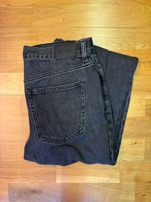 Weekday Galaxy 29/32 - Snygga svarta loose fit jeans från Weekday med klassisk femficksdesign och raka ben. Jeansen har normal passform och är tillverkade i slitstarkt denimtyg. Perfekt för dig som gillar en enkel och clean look med lite streetvibe. 29W/32L