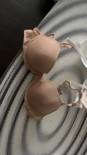 Oanvända! 2-pack basic bh toppar vit & beige - Säljer två basic bh:ar i ett 2-pack, en i vit och en i beige. Båda har vadderade kupor och justerbara axelband. Perfekta under t-shirts och linnen för en clean look. Dom är helt oanvända, lapp finns kvar och dom sitter fortfarande ihop! 