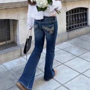 Blå bootcut jeans med broderade fickor - Snygga blå bootcut jeans med låg midja och broderade detaljer på bakfickorna. Storlek M men passar mig som har S