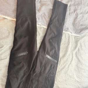 Svarta cargopants från 5.11 Tactical - Svarta cargopants från 5.11 Tactical med snygga sömmar och praktiska dragkedjefickor på benen. Byxorna är gjorda i ett slitstarkt syntetmaterial med mjuk fleece på insidan för extra komfort. Perfekt för dig som gillar funktionella och coola byxor.