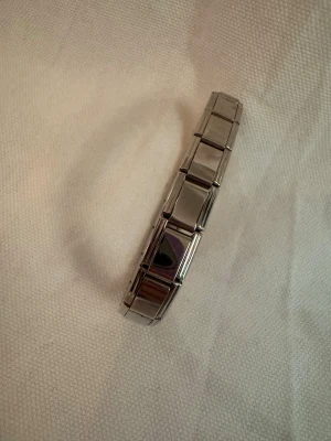 Silverfärgat länkat armband - Stilrent armband i silverfärgad metall med länkar som sitter ihop i ett elastiskt band. Designen är enkel och modern, perfekt för dig som gillar minimalistiska accessoarer. Passar både ensam eller i kombination med andra smycken.