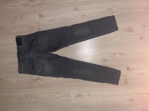 Replay Anbass grå jeans slim fit - Snygga Replay Anbass jeans i grå tvätt med klassisk femficksdesign och diskreta slitningar. Slim fit-modell med normal midja och raka ben. Jeansen har tydliga sömmar och metallknapp framtill. Perfekta för dig som gillar stilrena och moderna jeans.