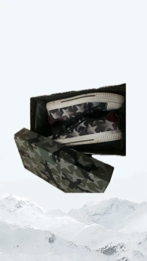 Valentino Garavani camo sneakers - Snygga sneakers från Valentino Garavani med stjärnmönster och camouflage i svart, grått och grönt. Skorna har snörning, rund tå och platt sula med nitar på hälen. Materialet är skinn och textil, och de har coola detaljer som sticker ut.