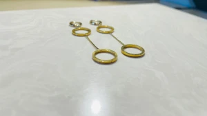 Guldiga statement örhängen med ringar - Säljer ett par unika örhängen i guldton med tre cirkelformade ringar i rad, sammanlänkade med tunna kedjor. De har en modern och stilren design som verkligen drar blickarna till sig. Perfekta för dig som gillar att sticka ut med accessoarer.