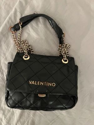 Valentino väska  - Säljer min  valentino väska! Har precis köpt en ny på grund av att denna väska verkligen är underbar. Väskan är sliten och som man ser är det en smink fläck i den. Jag väljer ändå att lägga ut ifall någon är intresserad köpt för 1200kr!