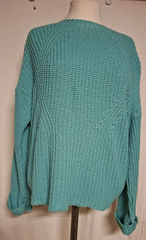 Turkos stickad tröja från Hailys - Säljer en chill turkos stickad tröja från Hailys i storlek L. Tröjan har grov ribbstickning, rund hals och långa ärmar med uppvikta muddar. Passformen är loose och den är perfekt för att mysa i under höst och vinter. Materialet känns mjukt och skönt mot huden.