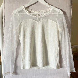 Vit spetsblus från Liz Lisa - Supersöt vit blus från Liz Lisa med transparenta prickiga meshärmar och spetsdetaljer vid halsen. Blusen har en liten rosett i nacken. 🤍 Perfekt för gyaru och coquette 🤍 Uppskattad storlek är S/M