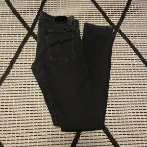 Svarta/mörkgråa Nudie jeans - Säljer dessa riktigt feta nudie jeans i mycket bra skick. De är är mörkgråa/svarta och är i storlek W32/L34. På bild två ser de lite missfärgade ut men det är inte så i verkligheten! Tveka inte med frågor!