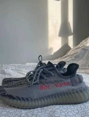 Adidas Yeezy Boost 350 V2 Beluga - Säljer ett par Adidas Yeezy Boost 350 V2 Beluga med grå och mörkgrå stickad ovandel, orange SPLY-350-tryck på sidan och genomskinlig ribbad platt sula. Skorna har snörning och en rund tå, tillverkade i syntetmaterial för en skön och modern look. Och har inte använd dem mycket och vi kan snacka om priset 