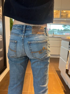 Jacob Cohen bootcut jeans med broderade fickor - Säljer ett par snygga blå jeans från Jacob Cohen  med bootcut passform. Jeansen har klassisk femficksdesign, coola broderade detaljer på bakfickorna och ett snyggt Jacob Cohen märke i linningen. Materialet är slitstarkt denim i bomull. Jeansen är handgjorda i Italien. 