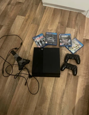 PlayStation 4 - Sony PlayStation 4 med två DualShock 4-kontroller, laddningsstation, strömkabel och fyra spel (FIFA 17, Call of Duty, Thief, The Division). Konsolen och tillbehören är i gott skick med mindre yttre slitage. Perfekt för spelkvällar med vänner.